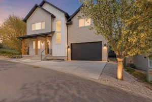 Modern facade with light-toned siding, dark trim, and prominent entryway featuring wood columns