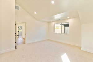 Spacious room featuring vaulted ceilings, recessed lighting, and a large window with white trim