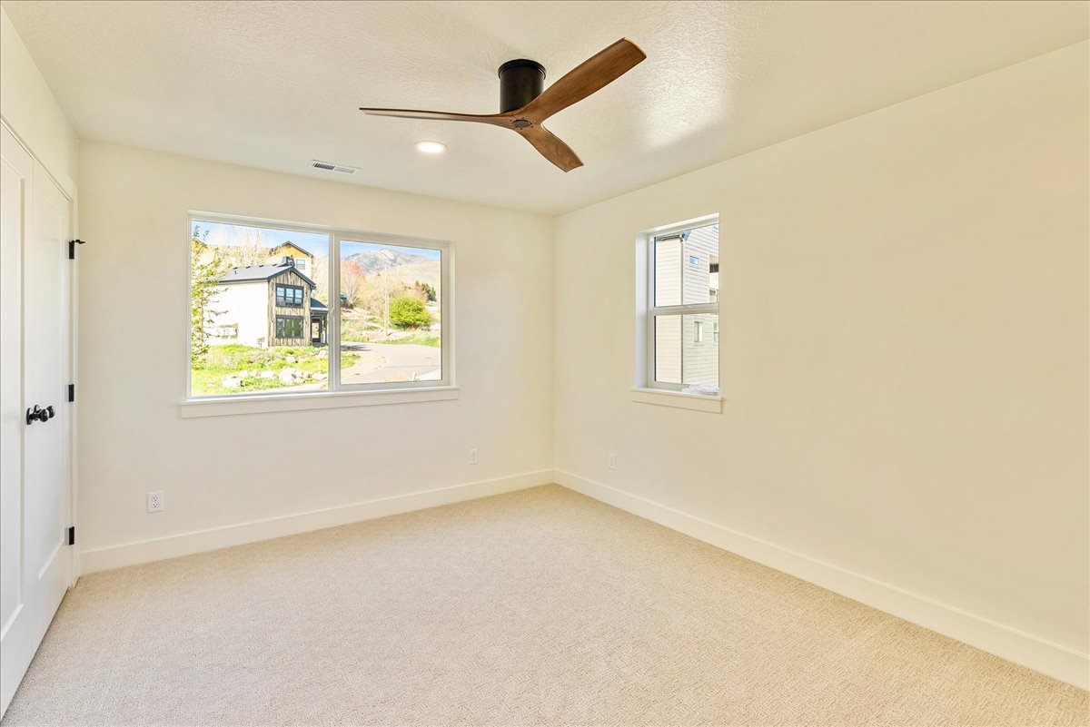 Carpeted room featuring a modern ceiling fan with wood-finish blades, recessed lighting, and white trim