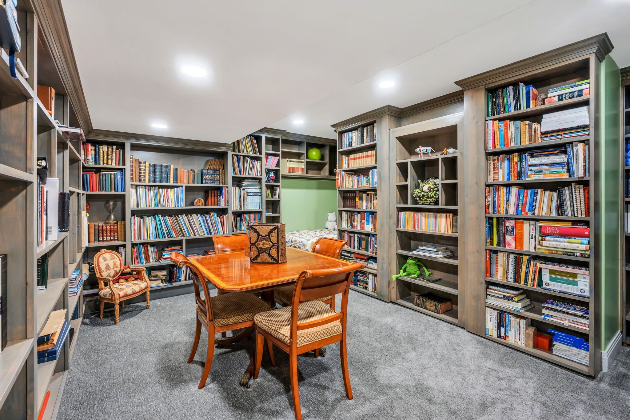 Dedicated library space featuring extensive built-in shelving, recessed lighting, and soft carpet flooring
