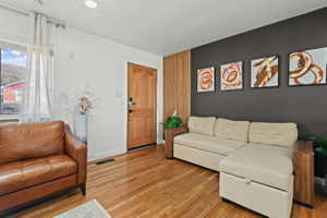 Hardwood-finish flooring extending throughout, complemented by a light-colored window with sheer curtains