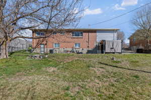 Expansive sloped yard featuring a mature deciduous tree and partial fencing