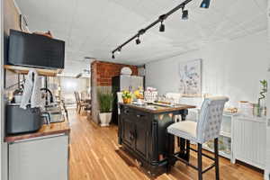 Kitchen featuring wood-finish flooring, an exposed brick wall, and a black track lighting system