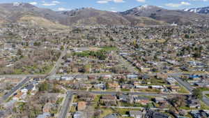 Residential neighborhood featuring a grid street pattern with various single-family homes, mature trees, and mountainous terrain in the background