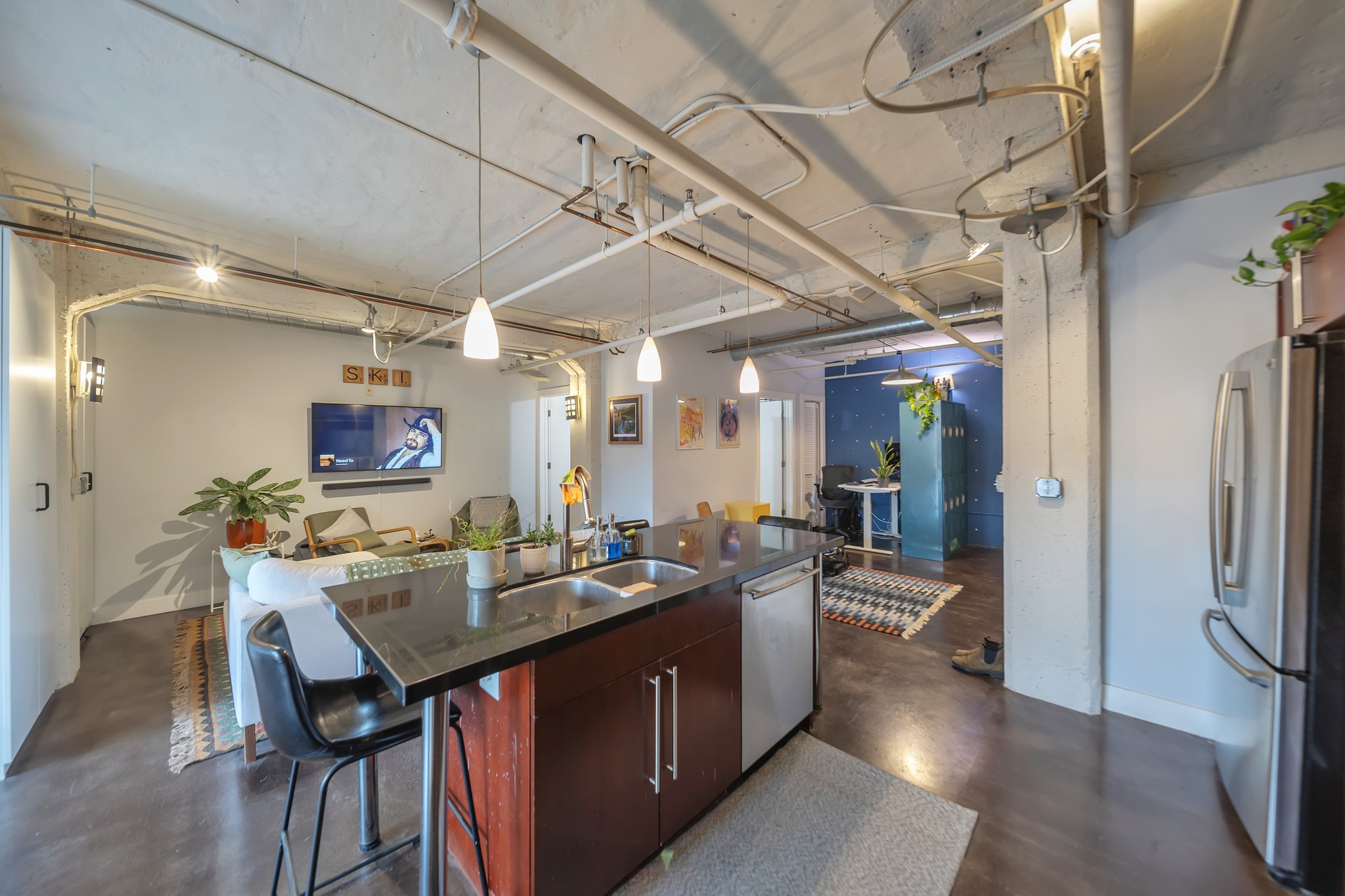 Kitchen island with a dark countertop and integrated stainless steel sink, featuring a stainless steel dishwasher