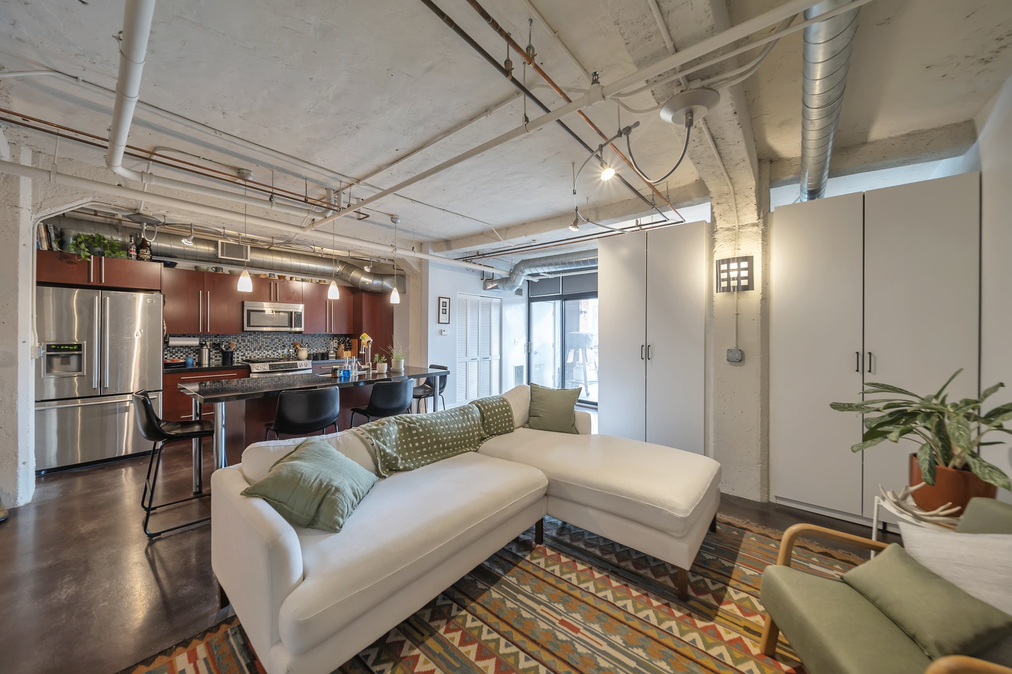 Open-concept living space featuring exposed ductwork and concrete ceilings
