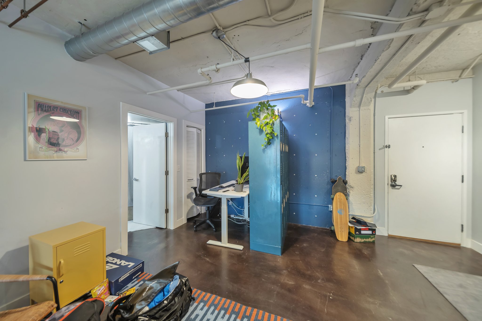 Concrete flooring with a polished finish, exposed ceiling ductwork, and a built-in office area with a blue accent wall