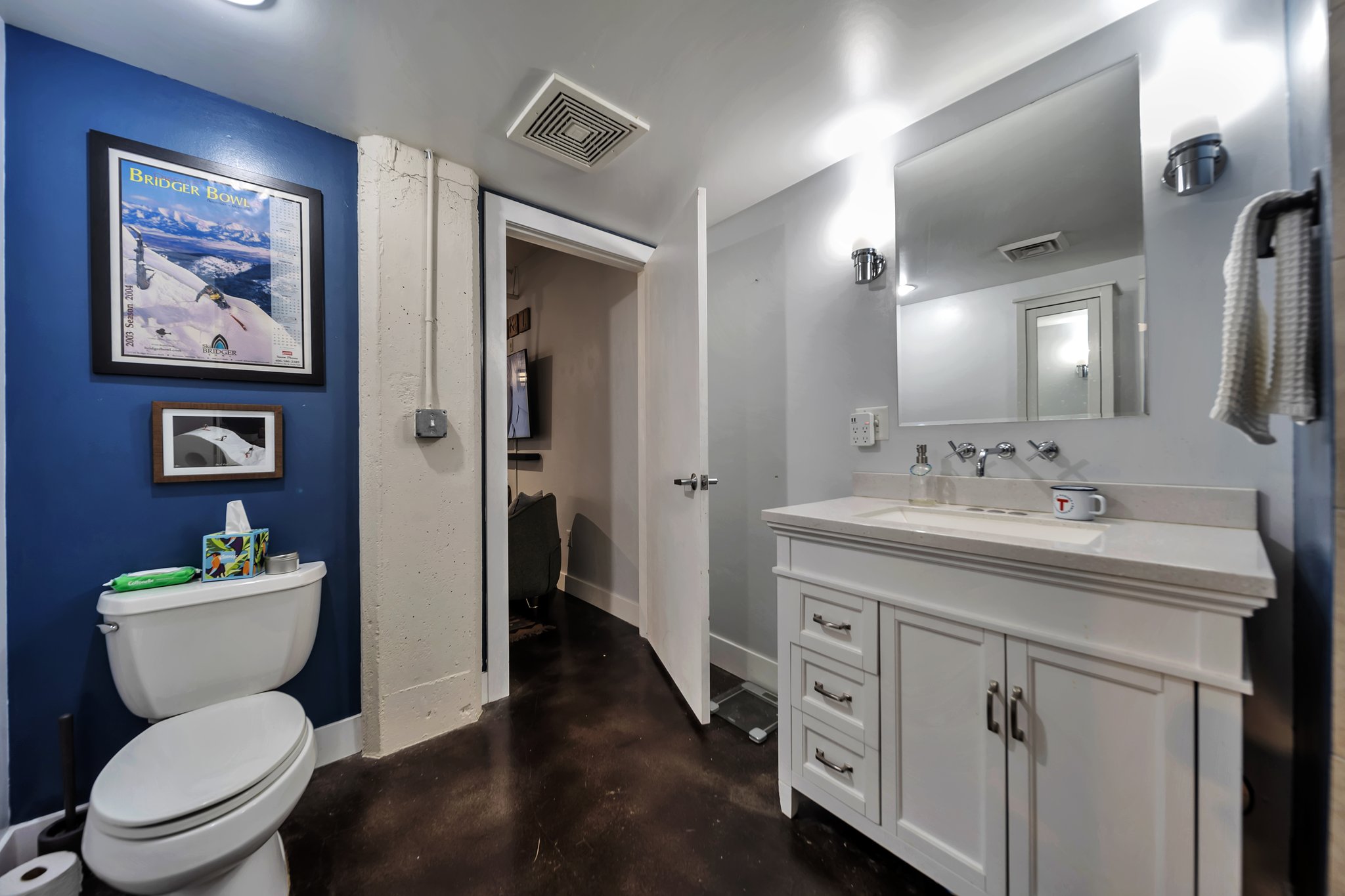 Bathroom featuring a white vanity with a stone-finish countertop, wall-mounted faucet, and a large mirror