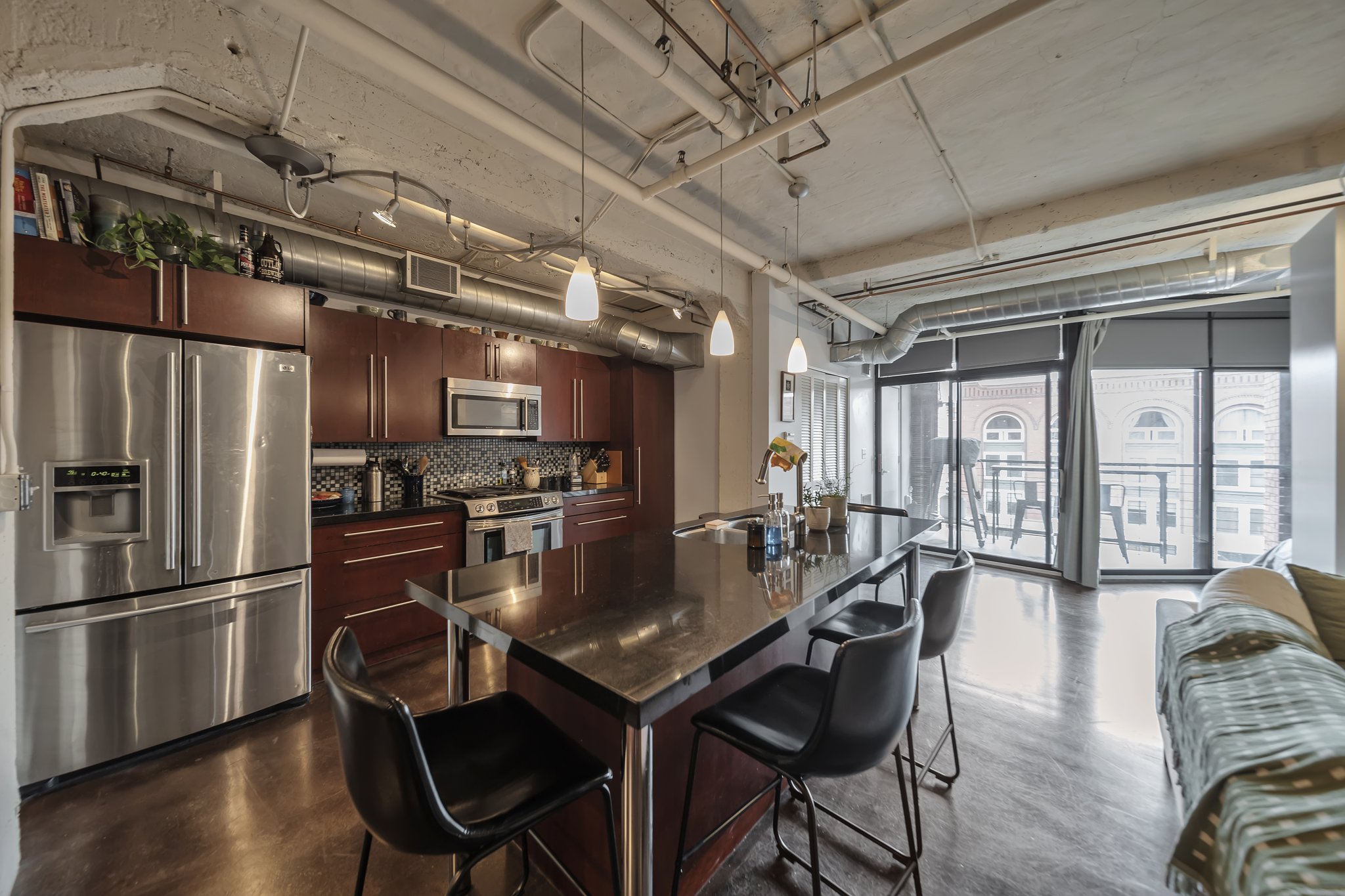 Modern kitchen featuring stainless steel appliances, dark wood cabinetry, and a patterned tile backsplash