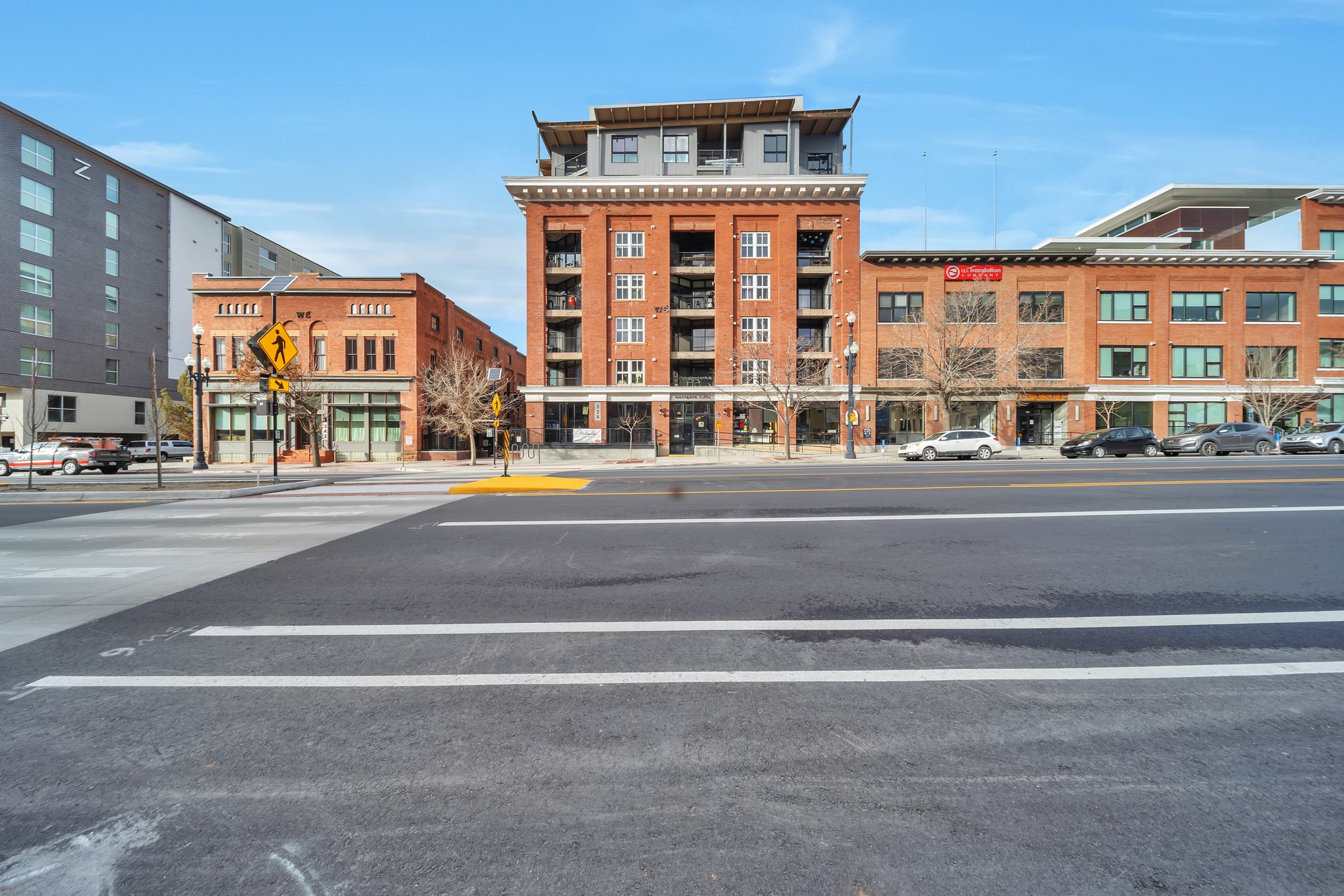 Brick-clad mixed-use buildings featuring multiple stories, balconies, and ground-level retail spaces