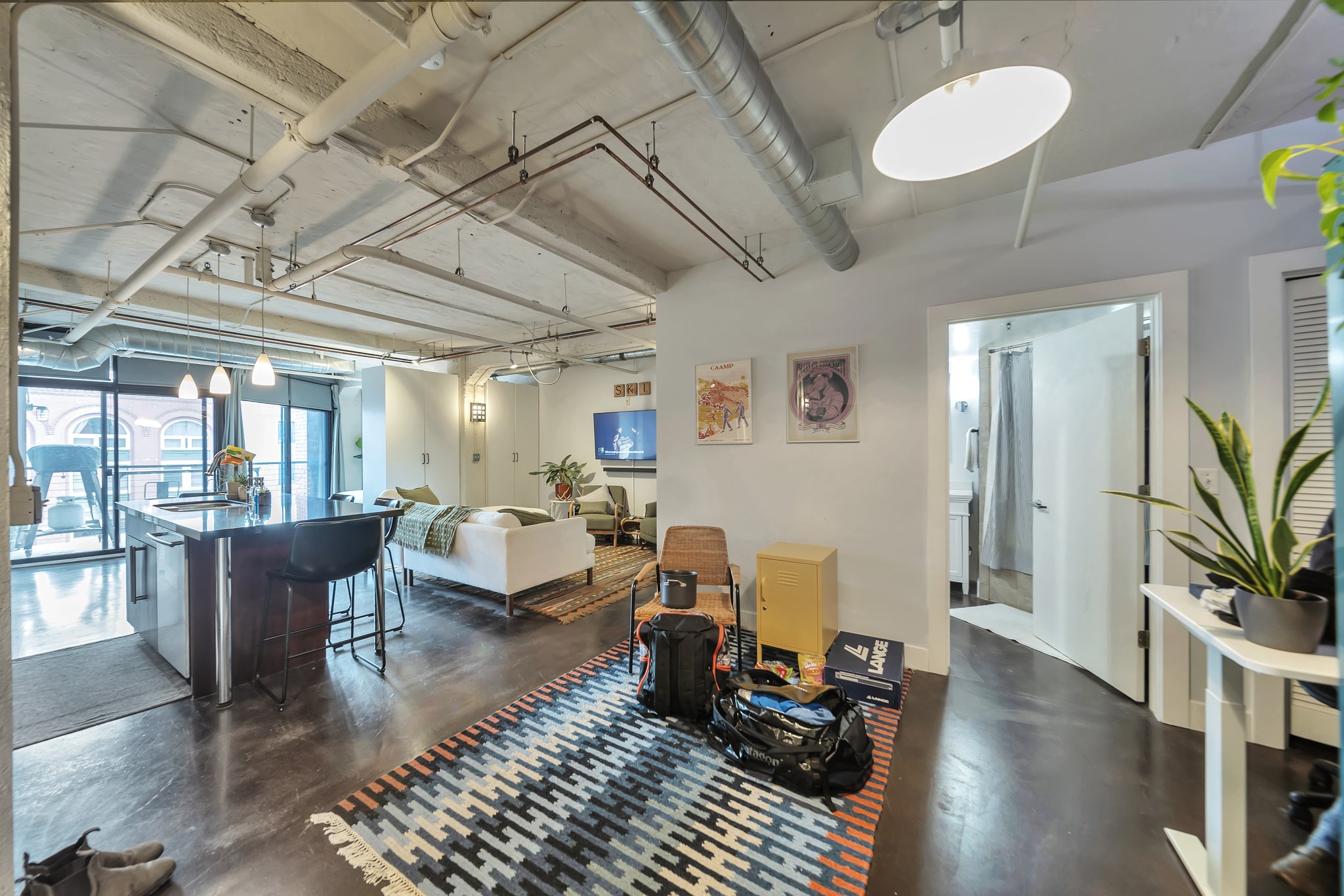 Open-concept living area featuring exposed ductwork and concrete ceilings