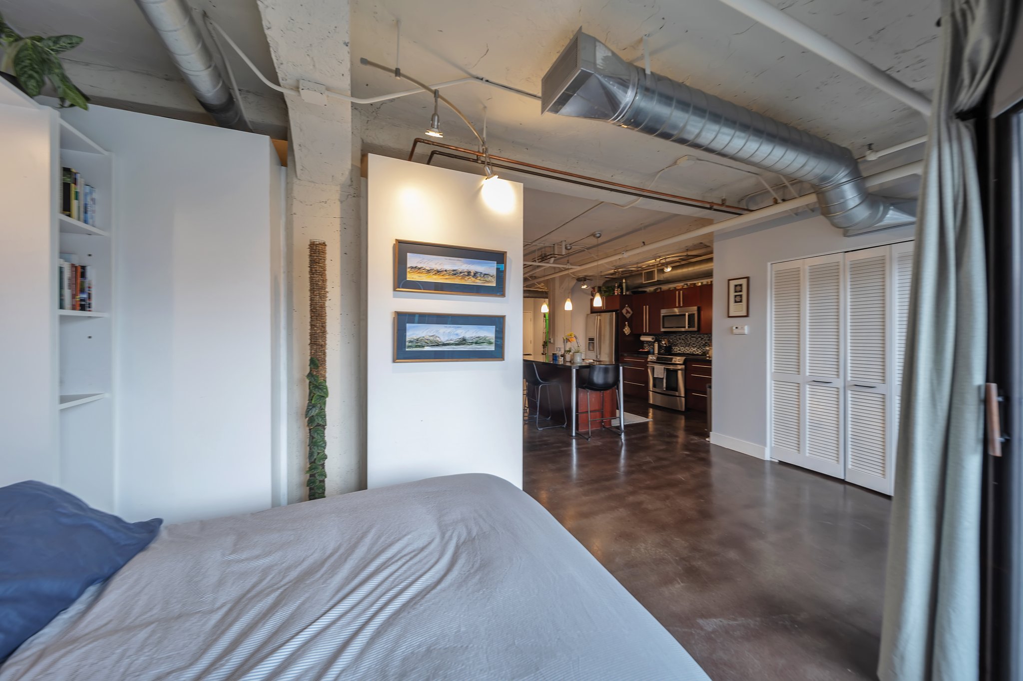 Open-concept living space featuring exposed ductwork, concrete ceiling, and dark polished flooring