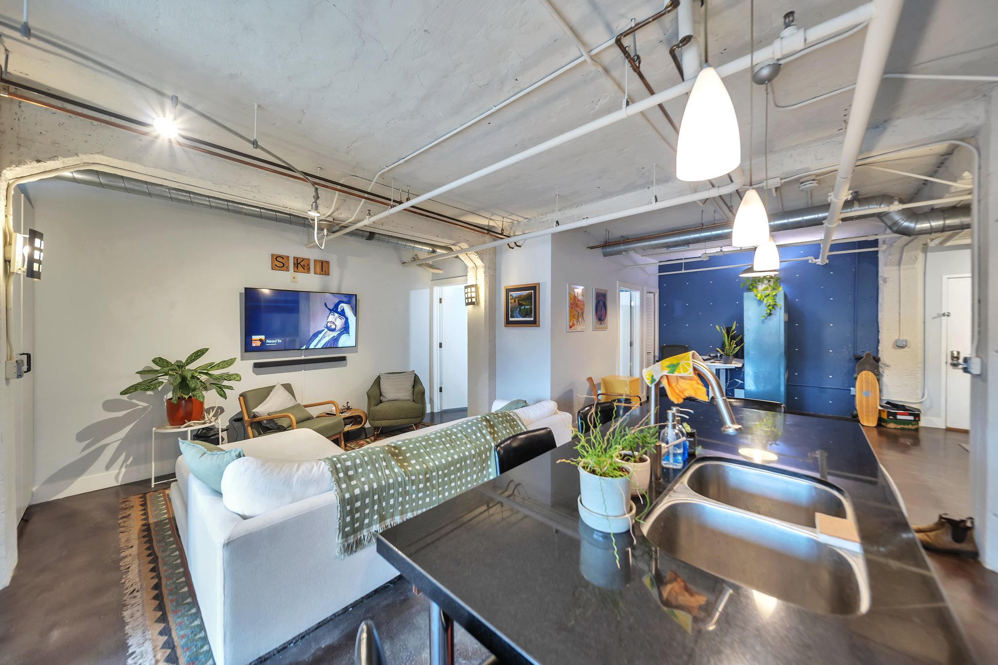 Open-concept living space featuring exposed industrial-style ceiling elements and track lighting