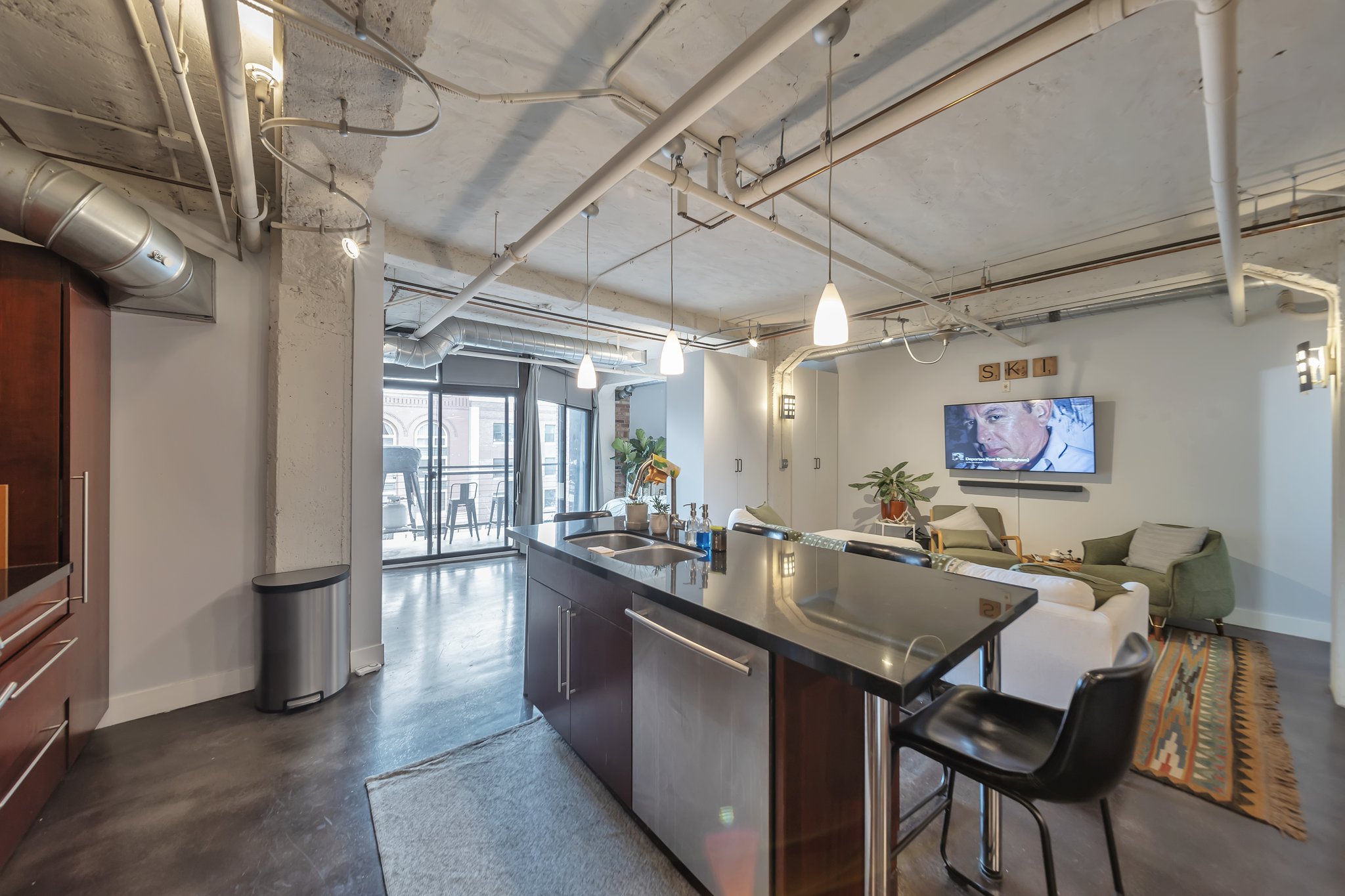 Open-concept living space with exposed concrete ceilings and industrial-style ductwork
