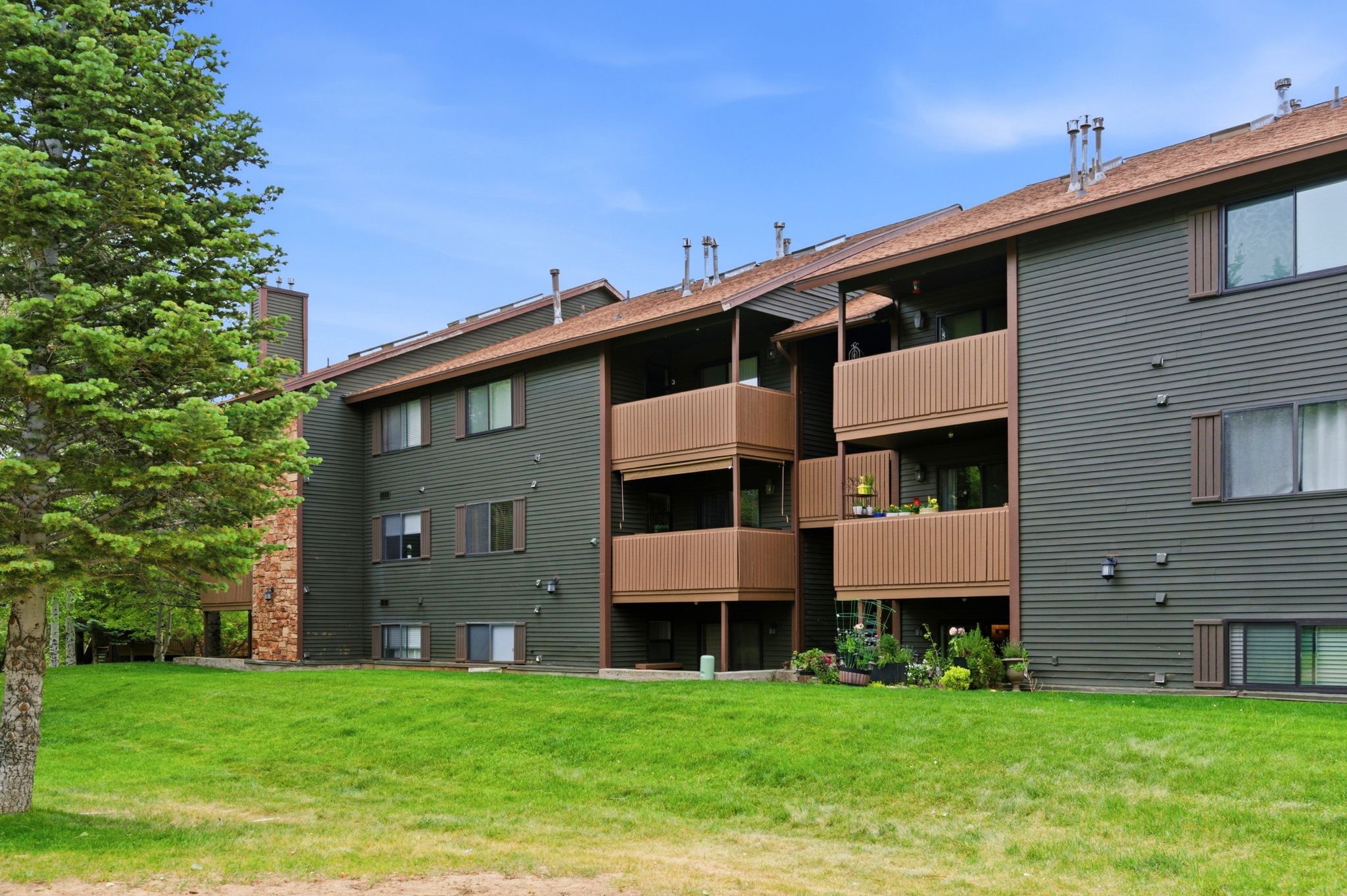 Multi-story building featuring dark green siding, brown trim, and multiple balconies