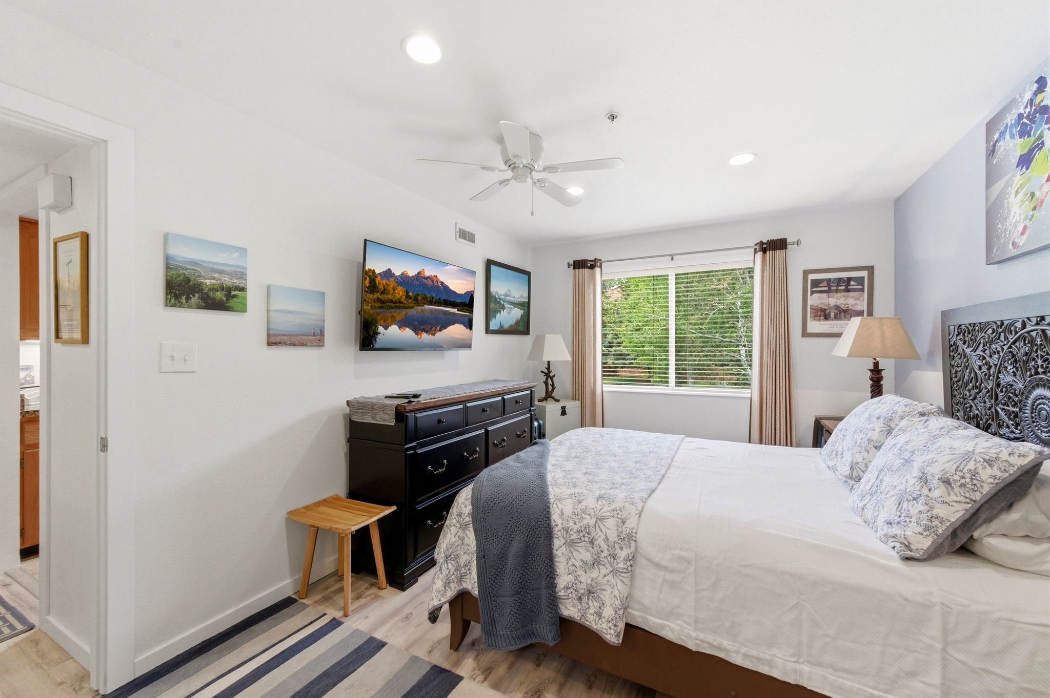 Well-lit room featuring wood-finish flooring and a ceiling fan