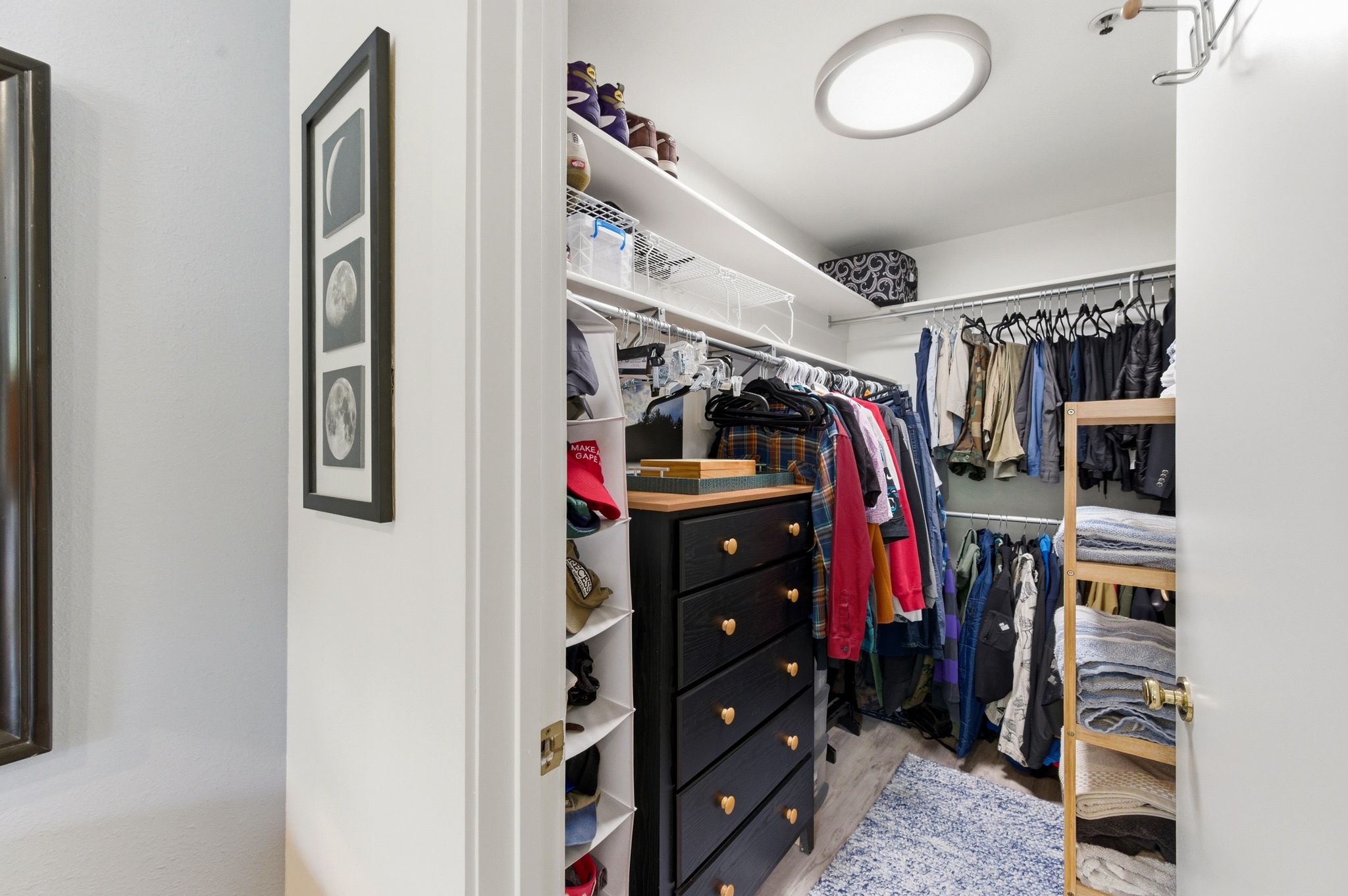 Walk-in closet featuring wood-finish flooring, recessed lighting, built-in shelving, and hanging storage