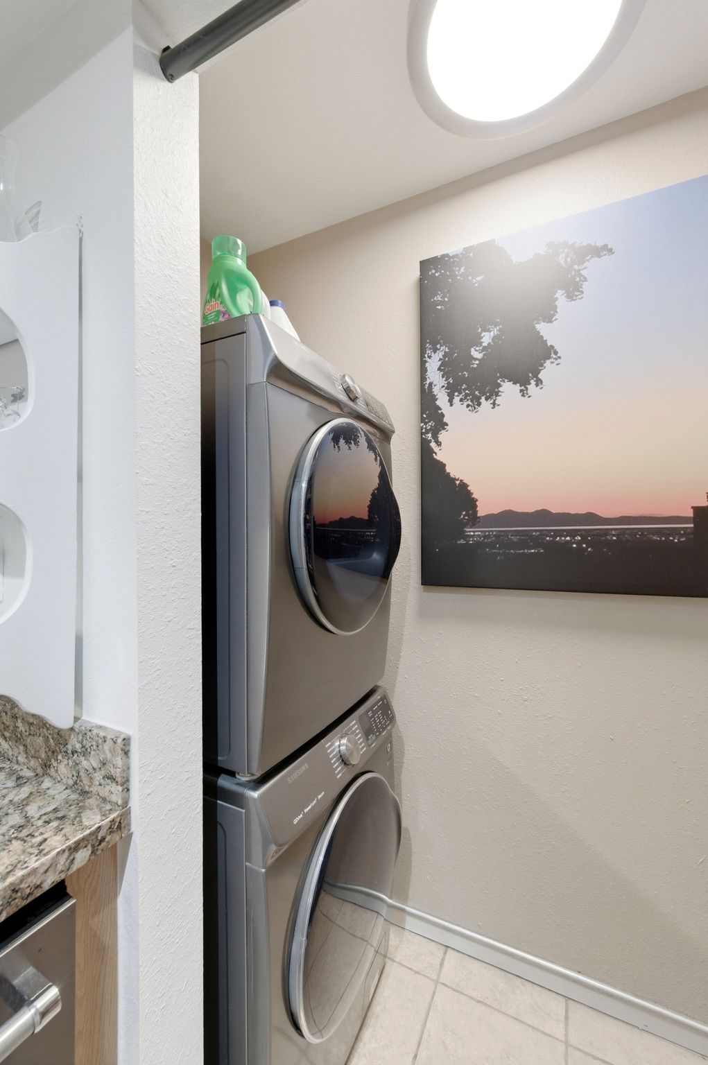 Dedicated laundry area featuring a stacked washer and dryer, recessed ceiling lighting, and tile flooring