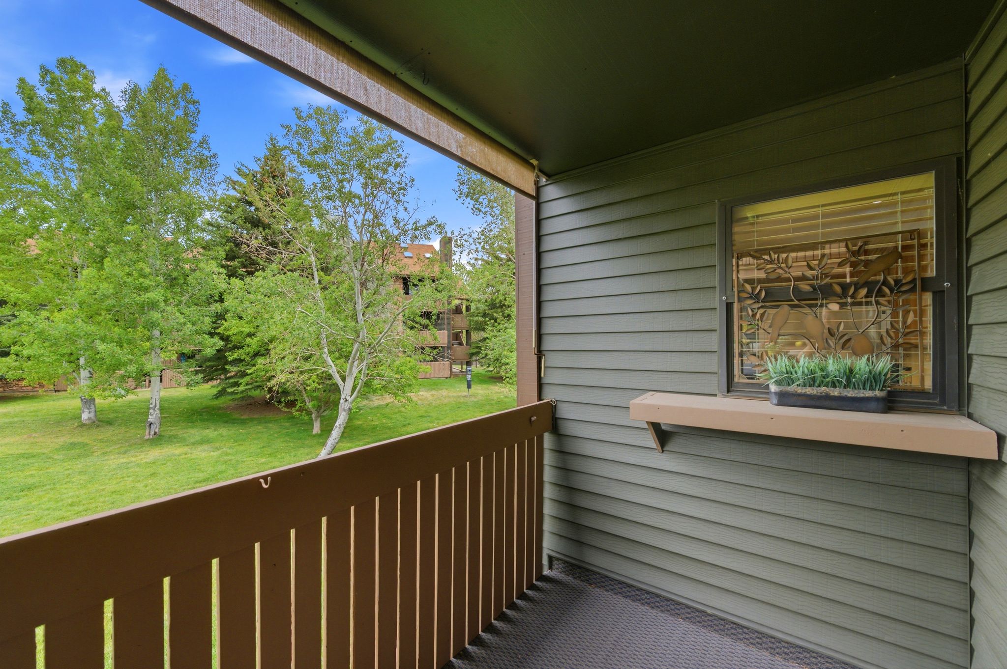 Private balcony featuring a railing with vertical balusters, a textured floor, and a window with blinds