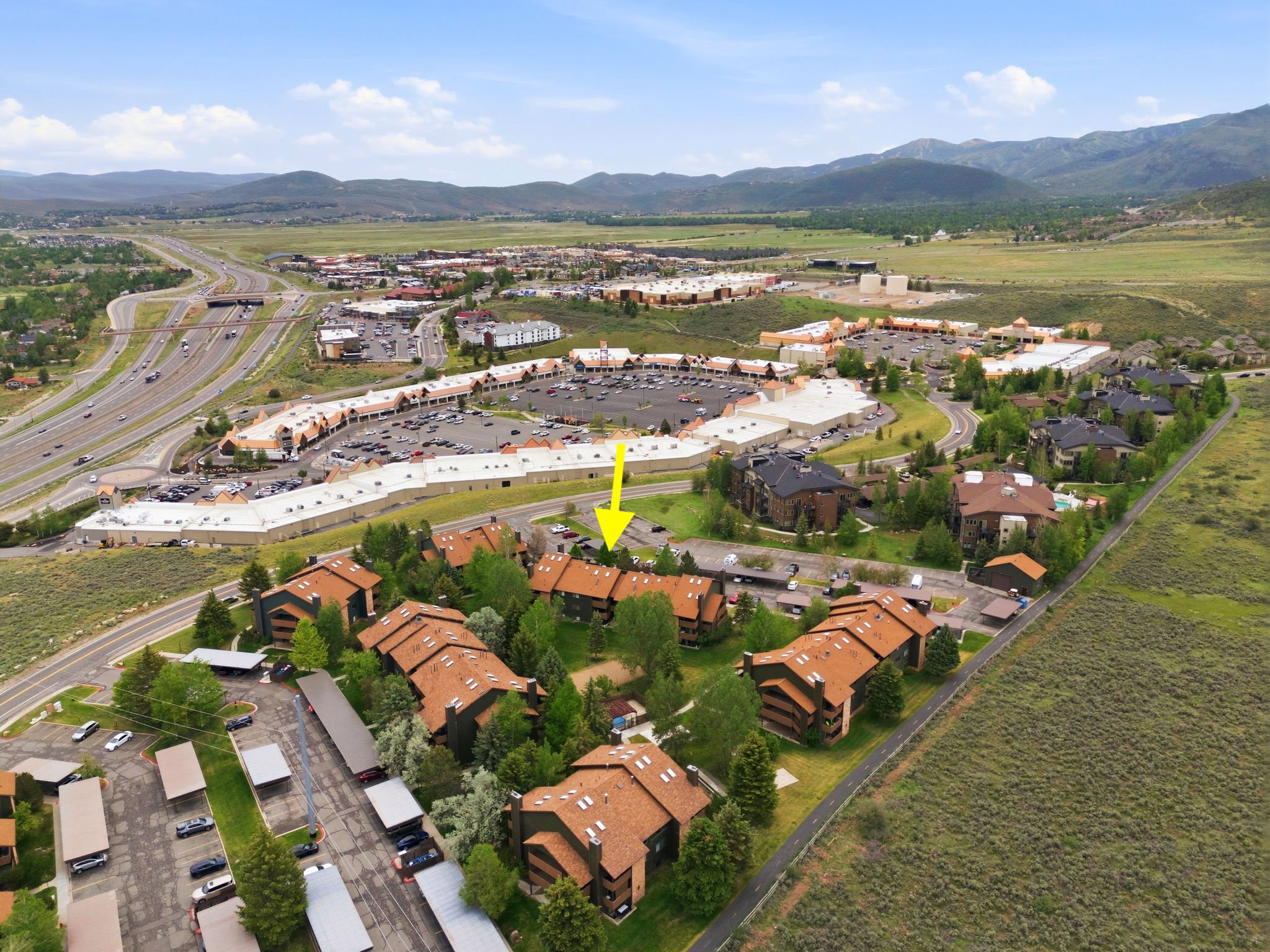 Aerial depiction of a residential community featuring multi-story buildings with pitched roofs and surrounding green spaces