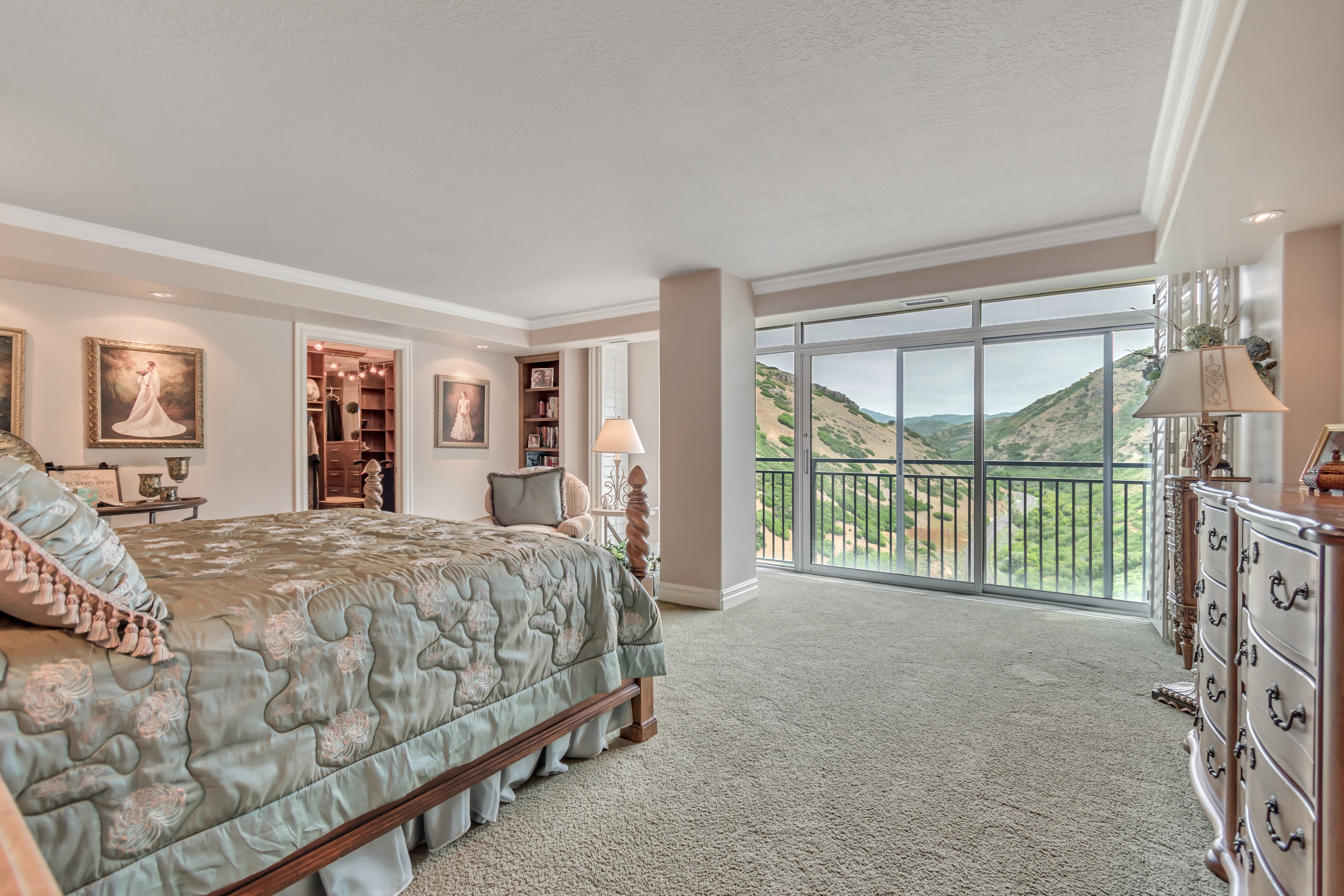 Master bedroom featuring a full-height glass sliding door, balcony with wrought iron railing, views of immigration canyon