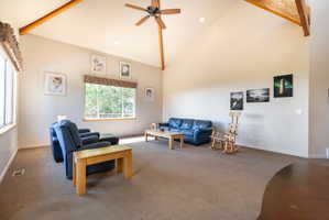 Vaulted ceilings with exposed wood beams, ceiling fan with light fixture, recessed lighting, expansive windows, and wall-to-wall carpeting
