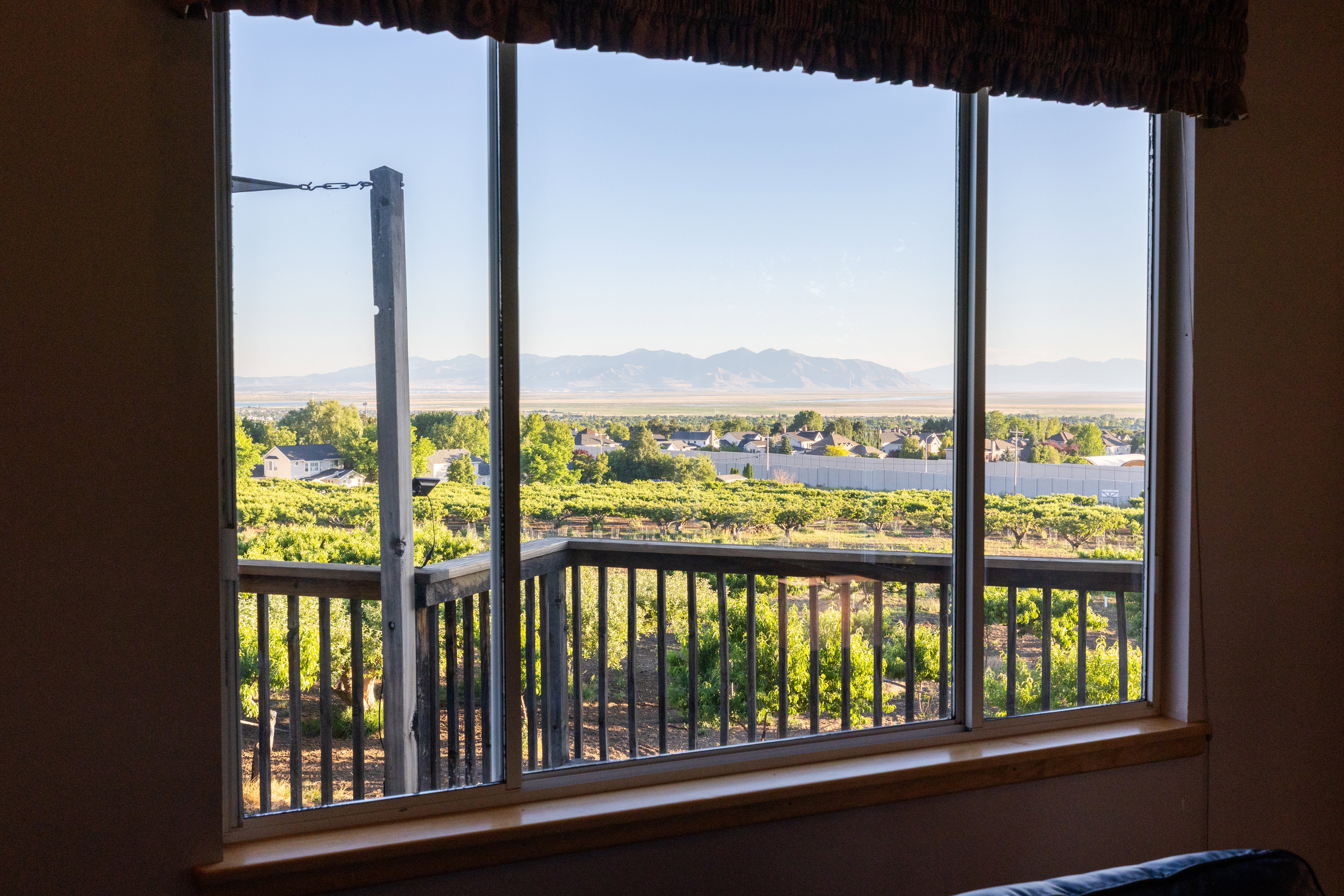 Expansive window featuring a distant mountain range, community landscape, and vineyard scenery