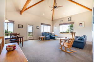 Spacious living area featuring a vaulted ceiling with exposed wood beams, recessed lighting, and a ceiling fan