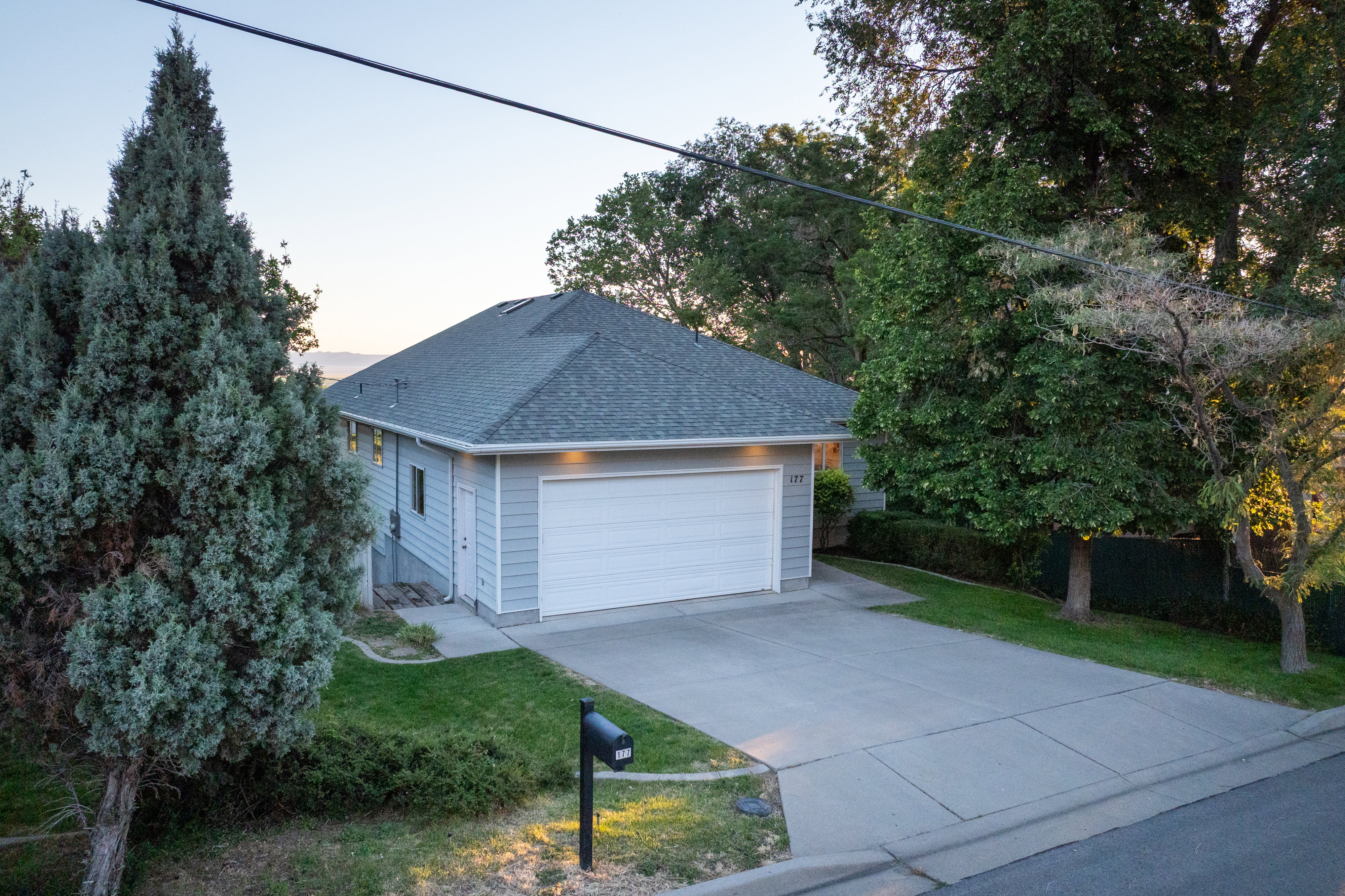 Light gray siding residence with an attached two-car garage, concrete driveway, and a dark gray shingle roof