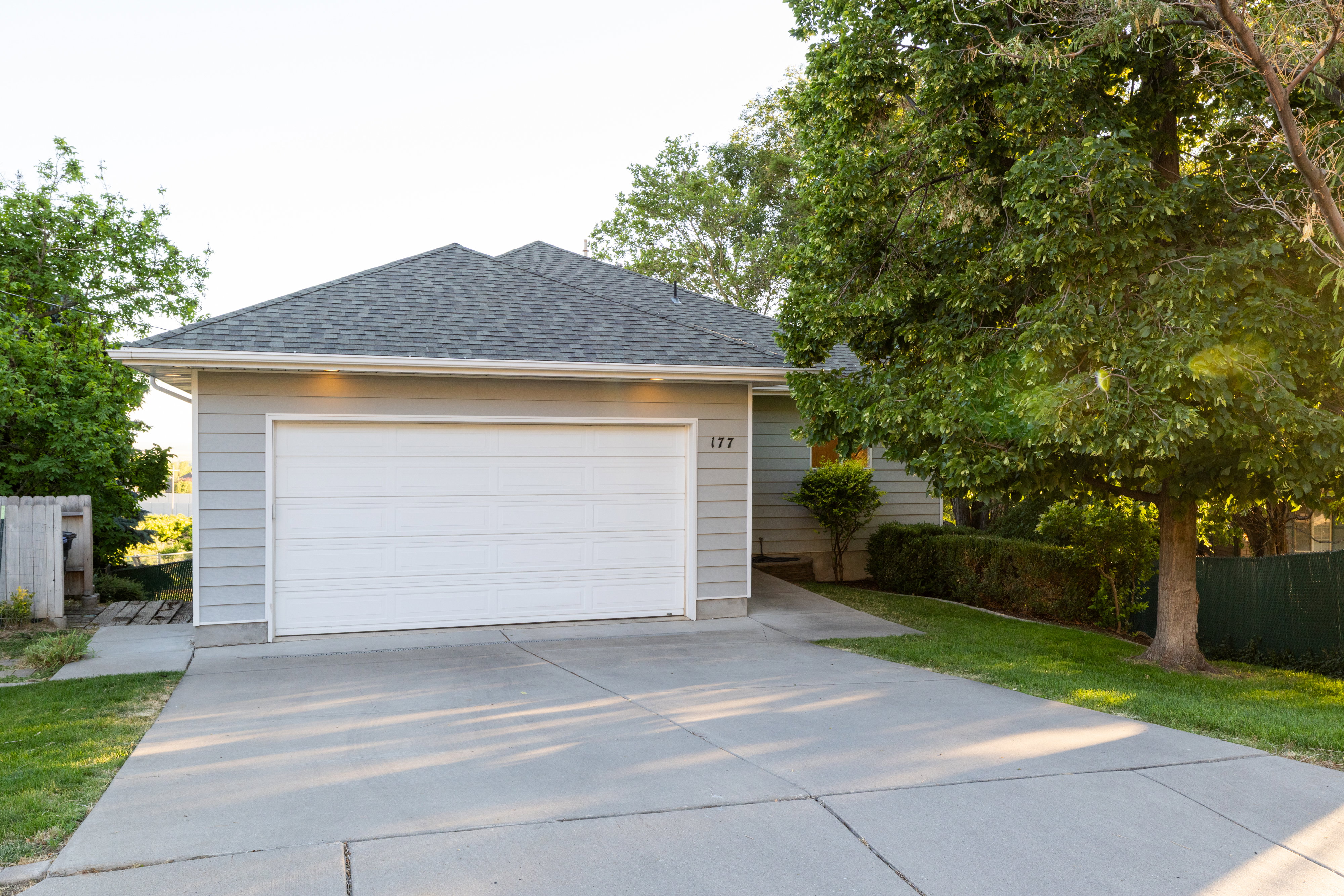 Single-story residence featuring light gray siding and a dark shingle roof
