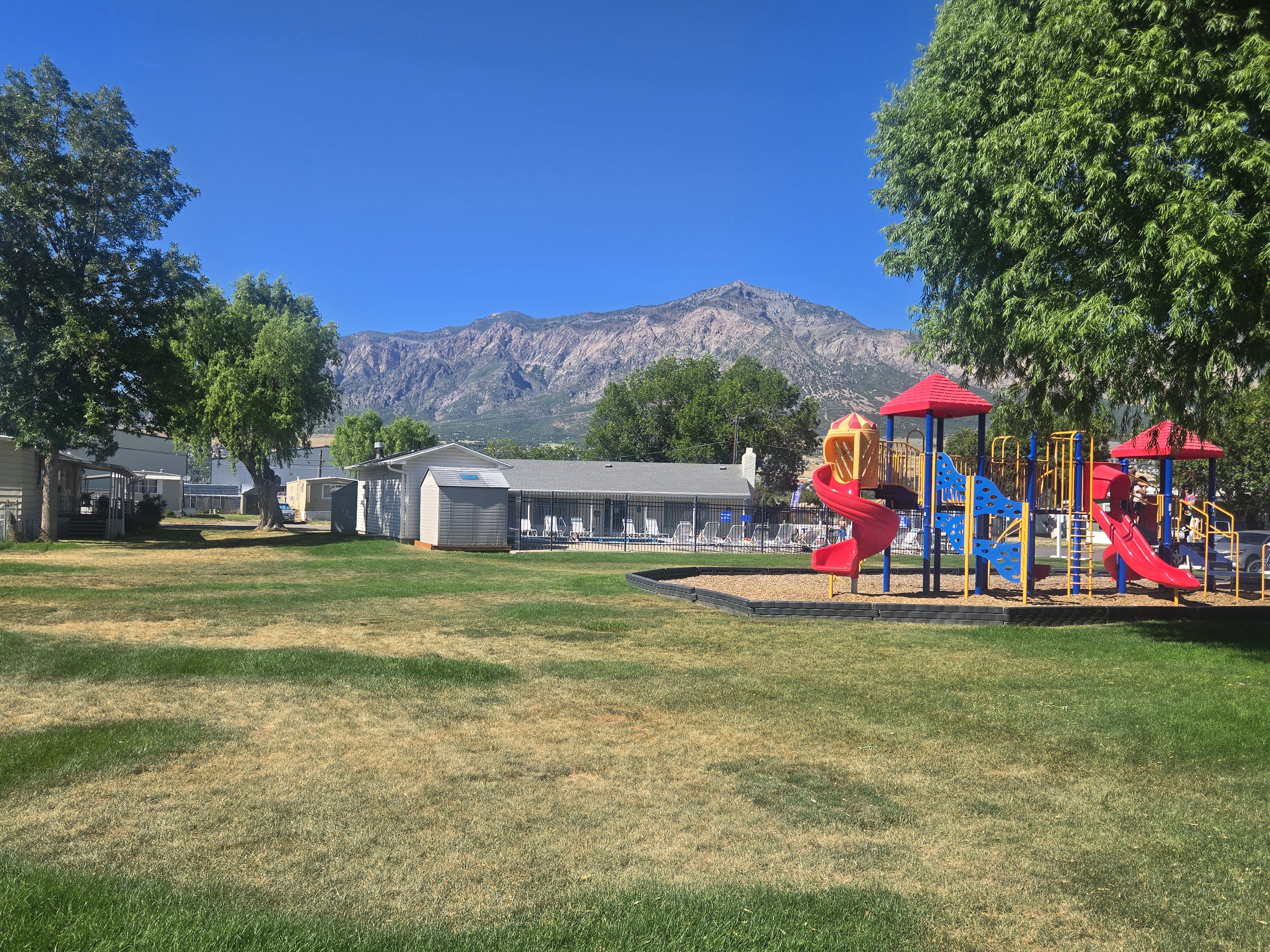 Expansive outdoor area featuring a colorful playground with slides and climbing structures on a wood chip base