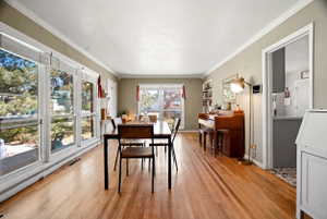 Bright interior space featuring wood-finish flooring, extensive window banks, crown molding, and built-in shelving