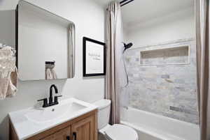 Bathroom featuring a wood-finish vanity with an integrated sink, matte black faucet, and a wall-mounted rectangular mirror