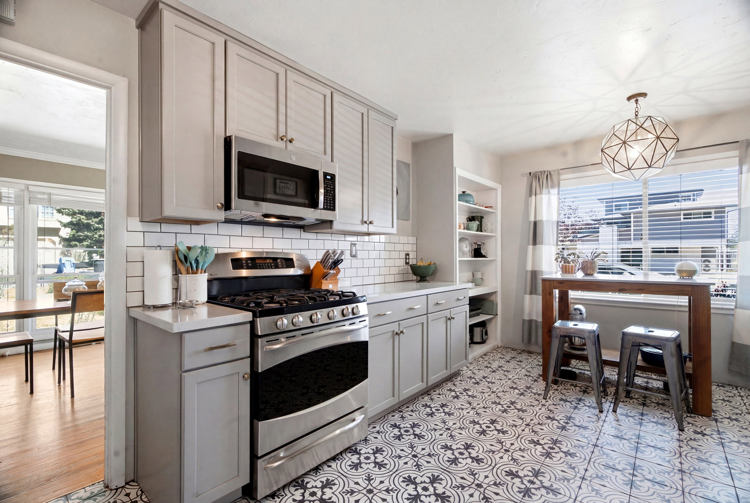 Kitchen featuring patterned floor tile, light gray cabinetry, white subway tile backsplash, stainless steel gas range, and a built-in microwave