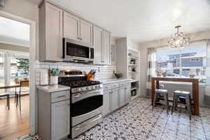 Kitchen featuring patterned floor tile, light gray cabinetry, white subway tile backsplash, stainless steel gas range, and a built-in microwave