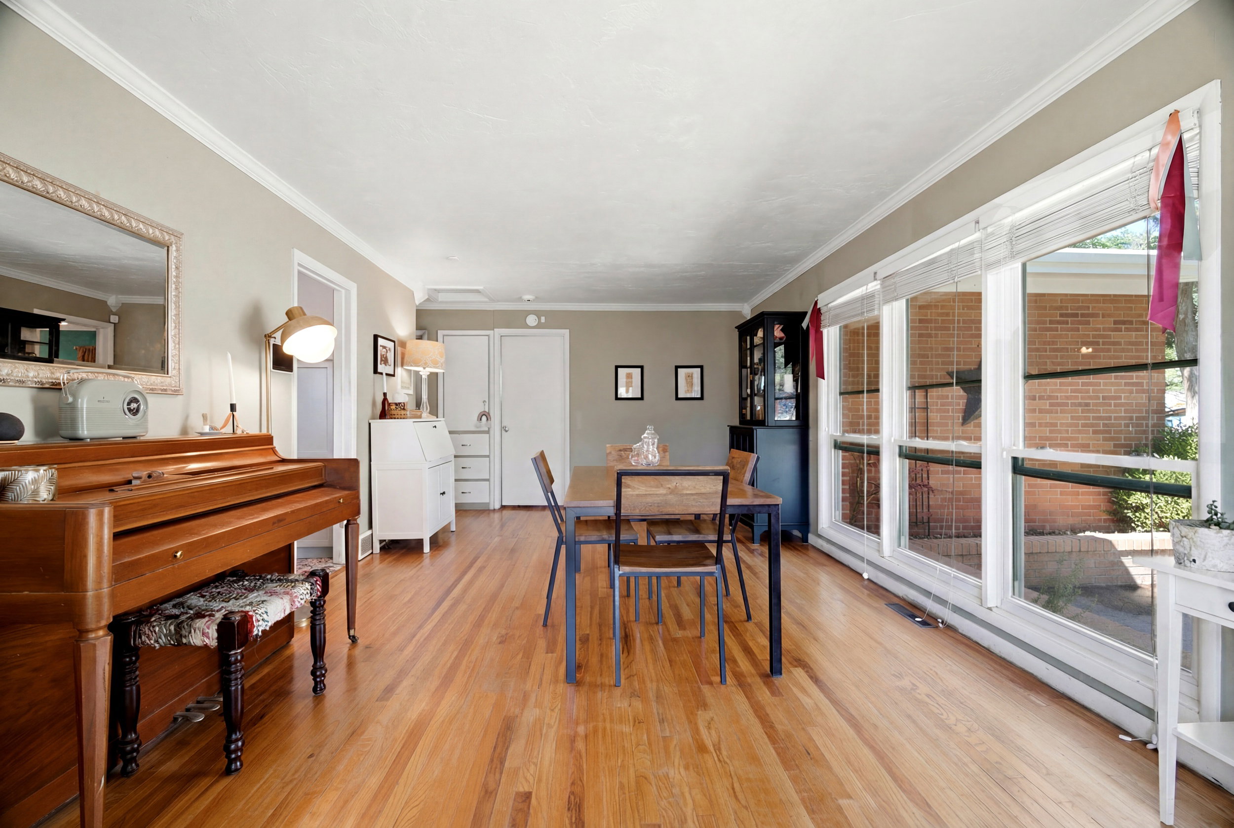 Spacious room featuring wood-finish flooring, a wall of large windows, and crown molding