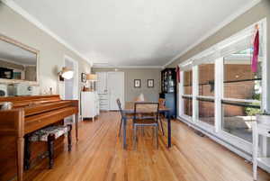 Spacious room featuring wood-finish flooring, a wall of large windows, and crown molding
