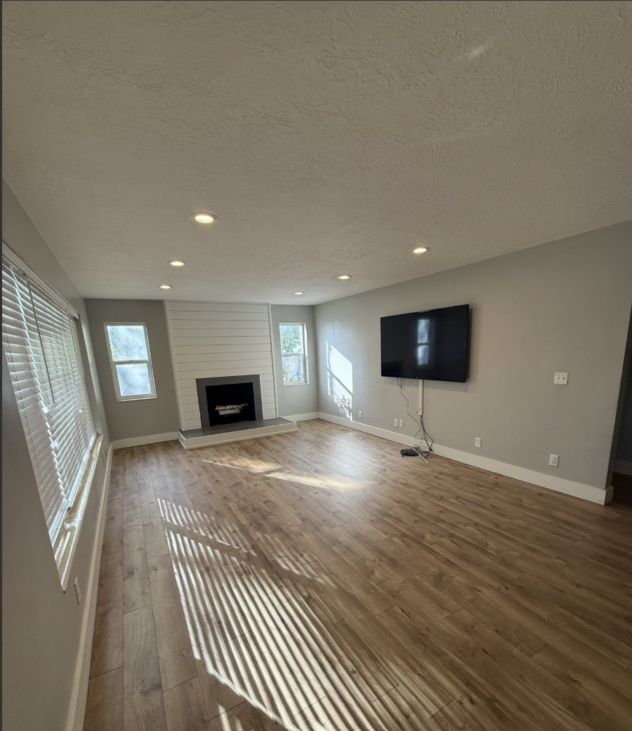 Spacious room featuring wood-finish flooring, recessed lighting, and multiple windows with blinds