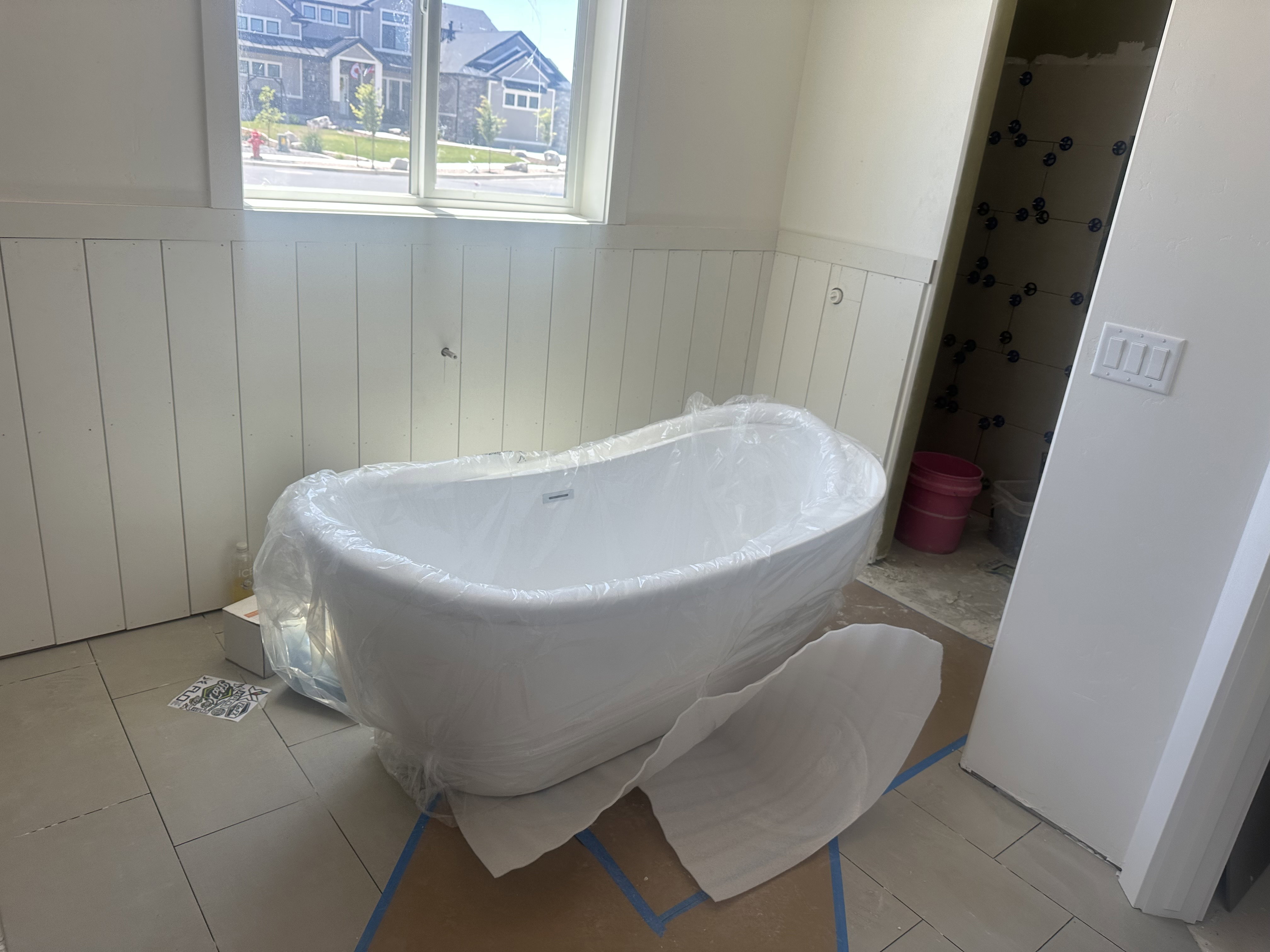 Freestanding soaking tub centered in a bathroom featuring board and batten wainscoting