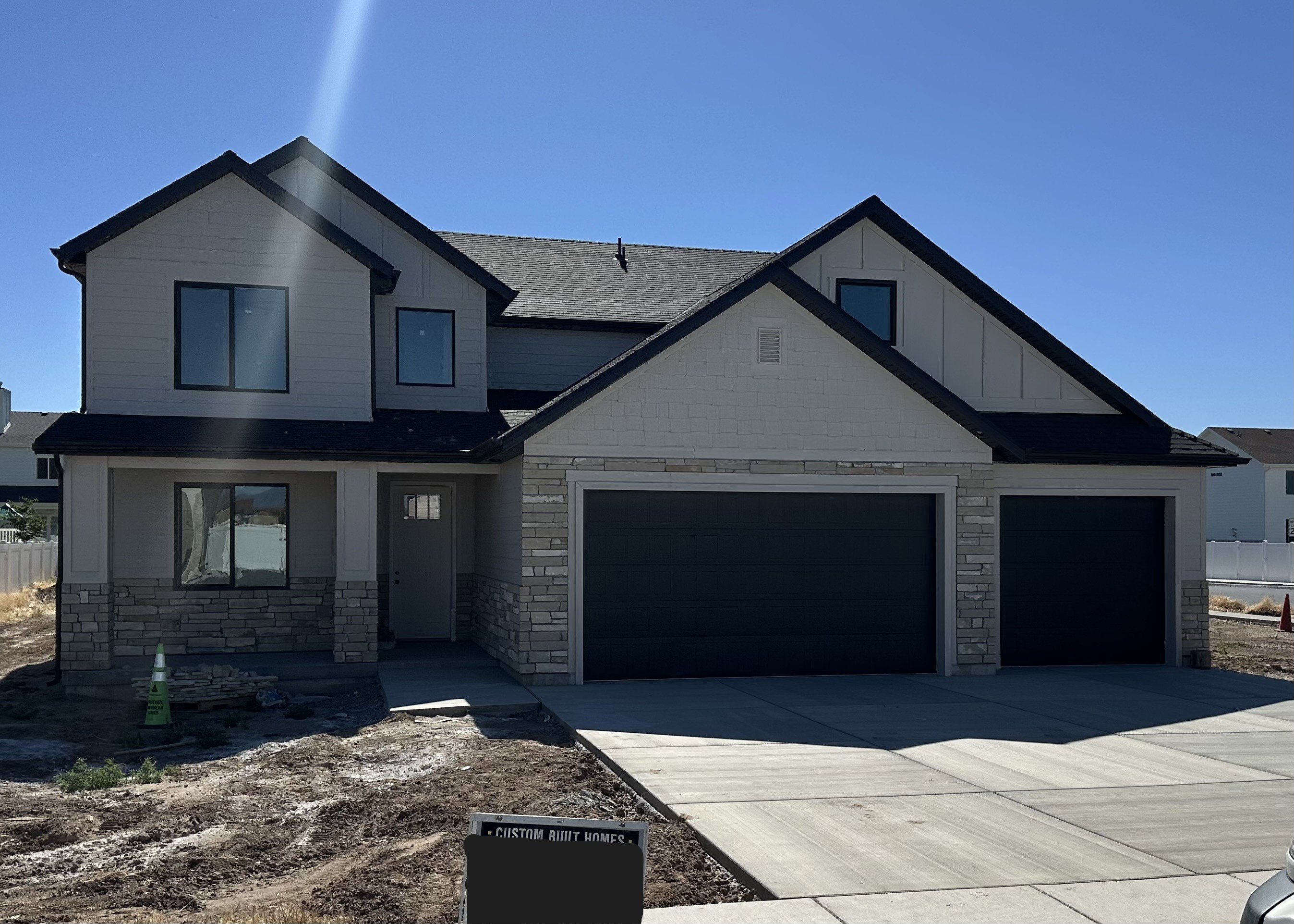 Contemporary two-story residence featuring a combination of light-toned siding, dark trim, and stone accents
