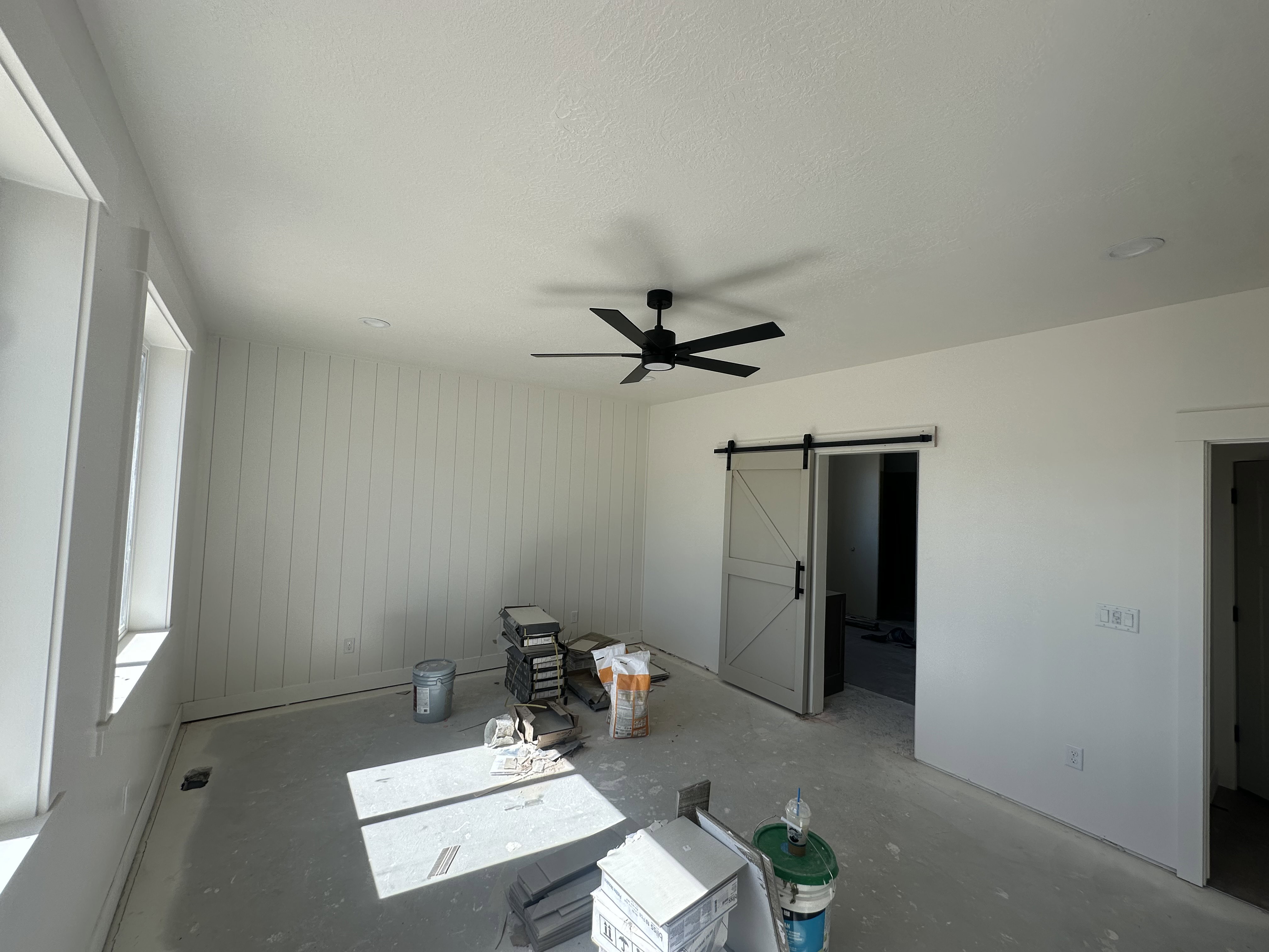 Spacious interior room featuring a modern ceiling fan, recessed lighting, and a barn door entry