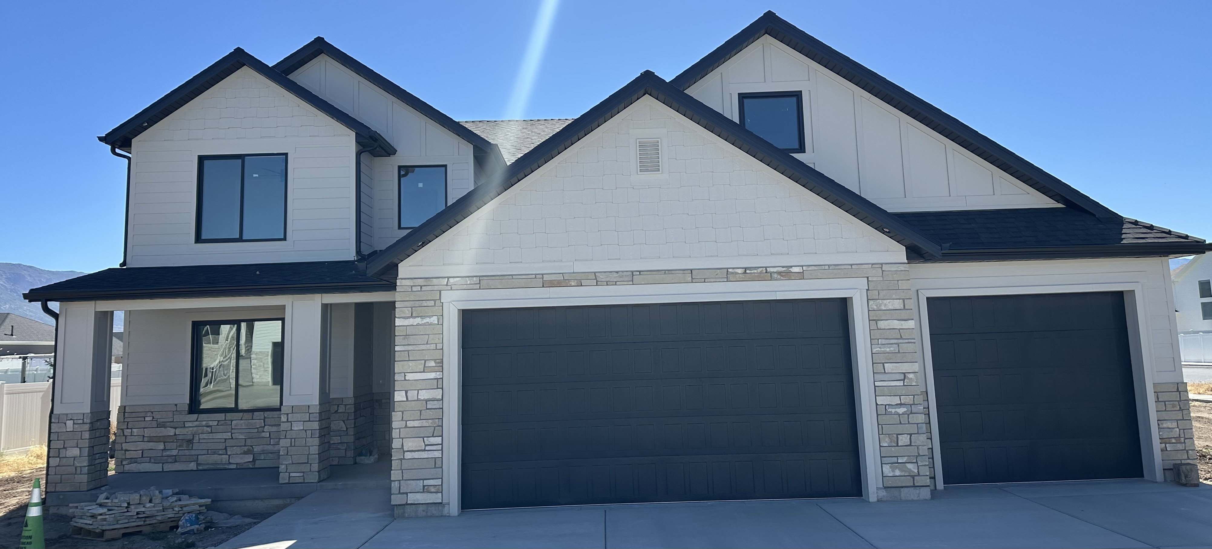 Modern farmhouse exterior featuring black-framed windows, a covered front entry, and a two-car garage with dark paneled doors