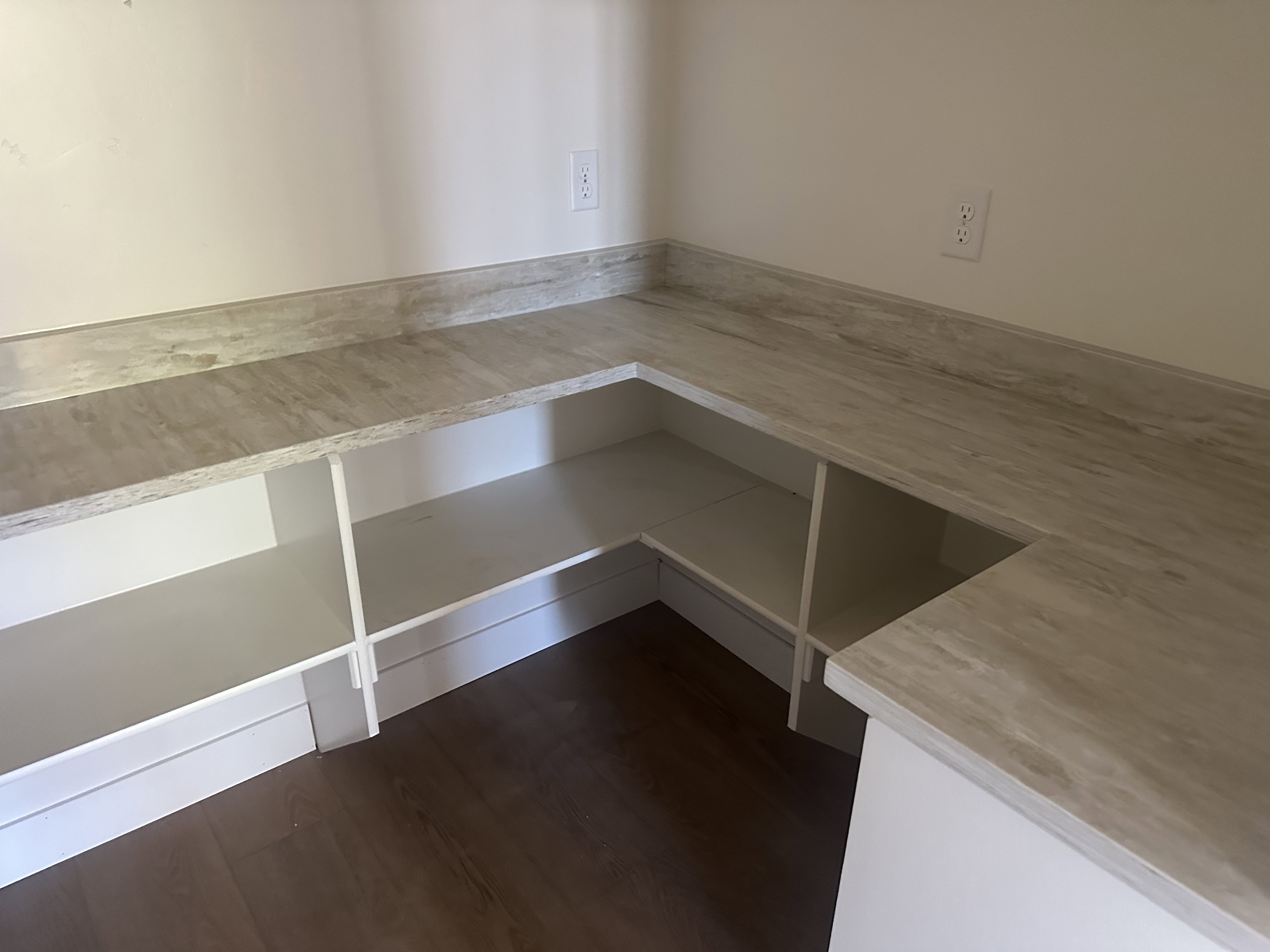 Wraparound counter with a light-toned, veined surface, complemented by white open shelving below