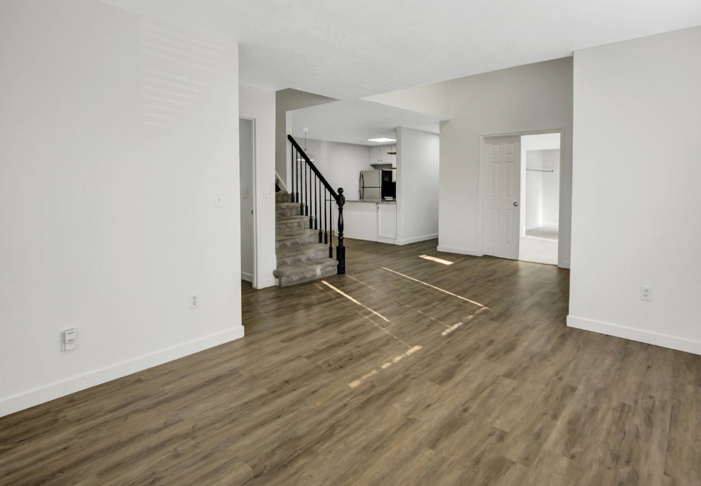 Open-concept living space featuring wood-finish flooring and bright white walls
