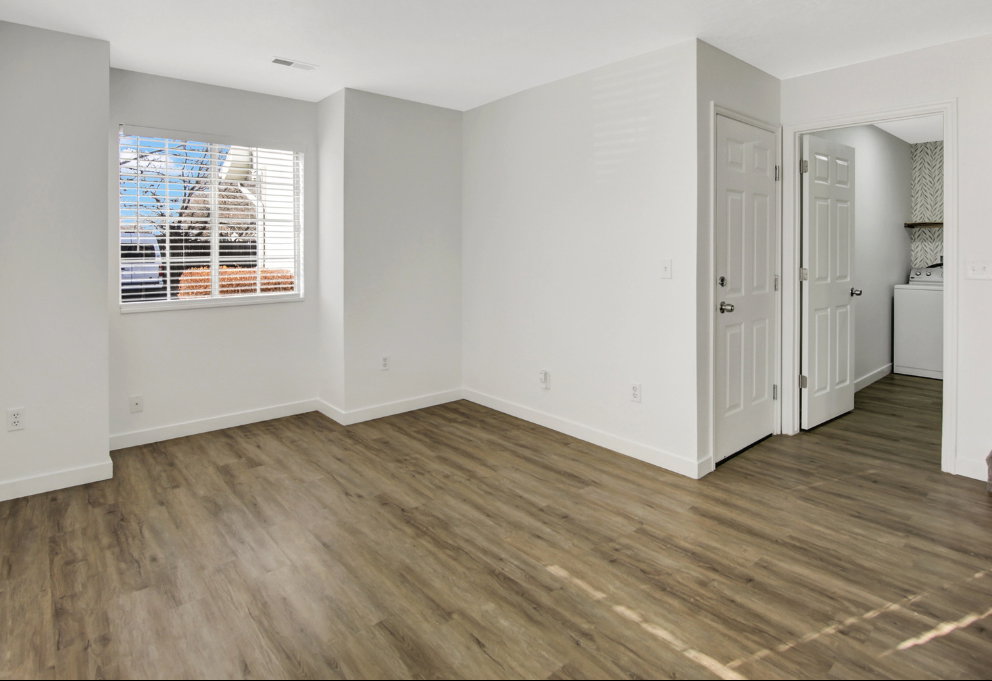 Spacious room featuring wood-finish flooring, white baseboards, and a window with horizontal blinds