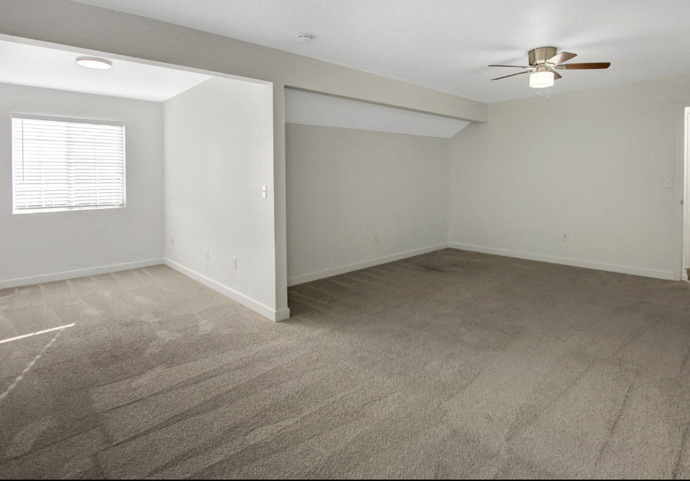 Spacious carpeted interior featuring a ceiling fan, recessed lighting, and window blinds