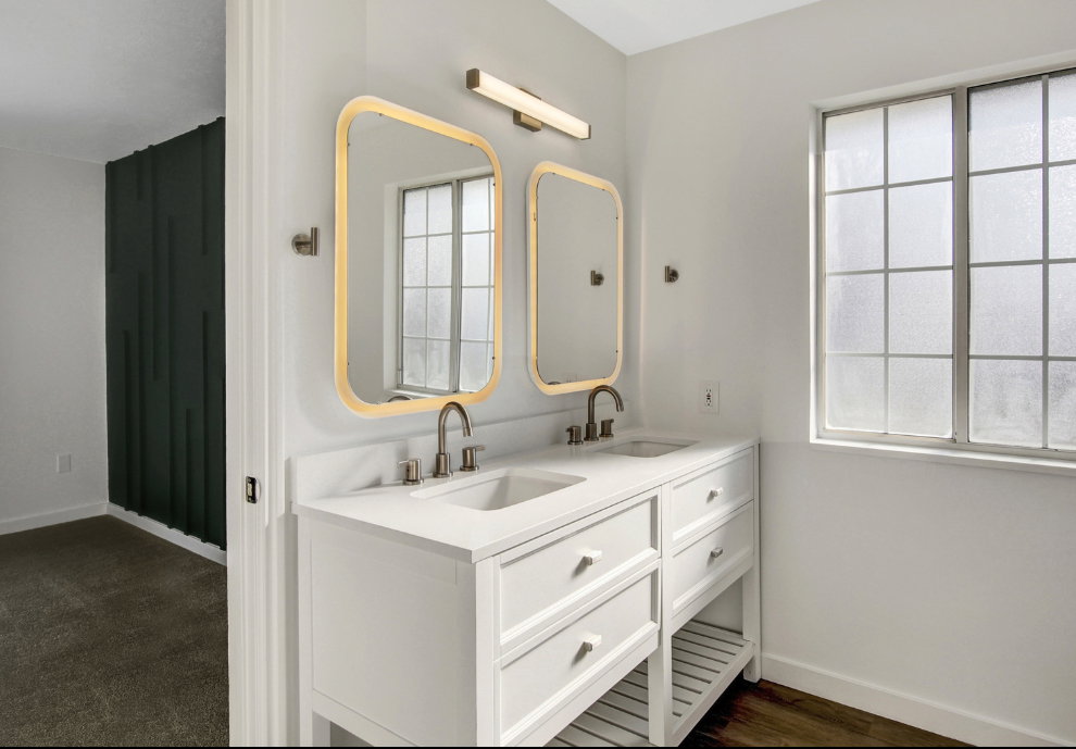 Double vanity with white cabinetry and integrated sinks, brushed nickel fixtures, and illuminated rectangular mirrors