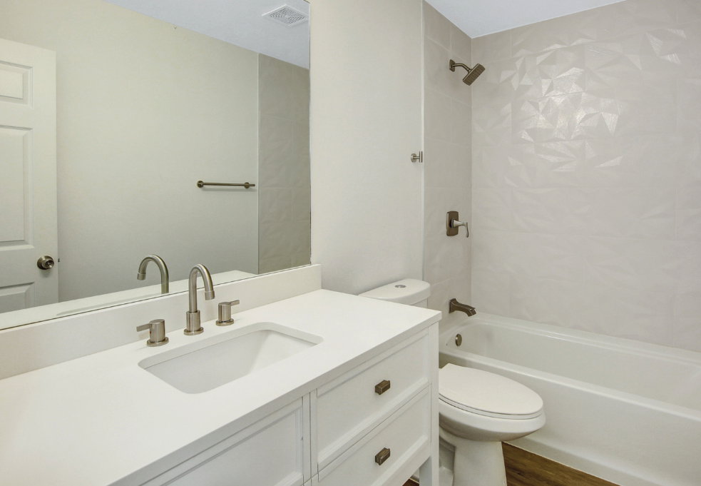 Bathroom featuring a white vanity with integrated sink, brushed nickel hardware, and a framed mirror