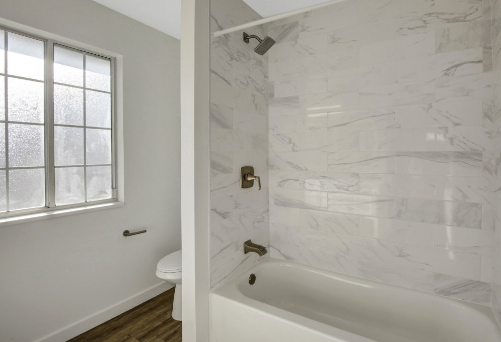 Bathtub with tile surround, bronze fixtures, and showerhead