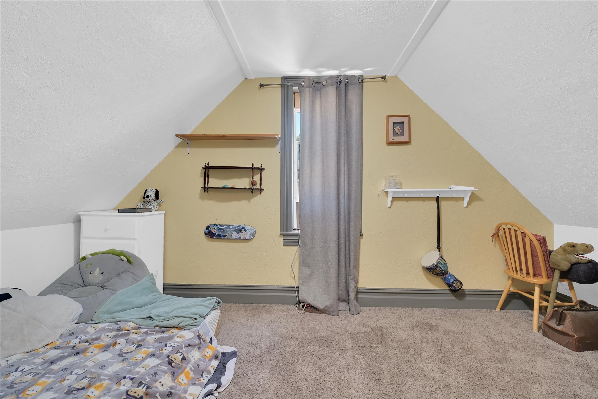 Attic room featuring a single window, sloped ceilings, and neutral-toned carpeting